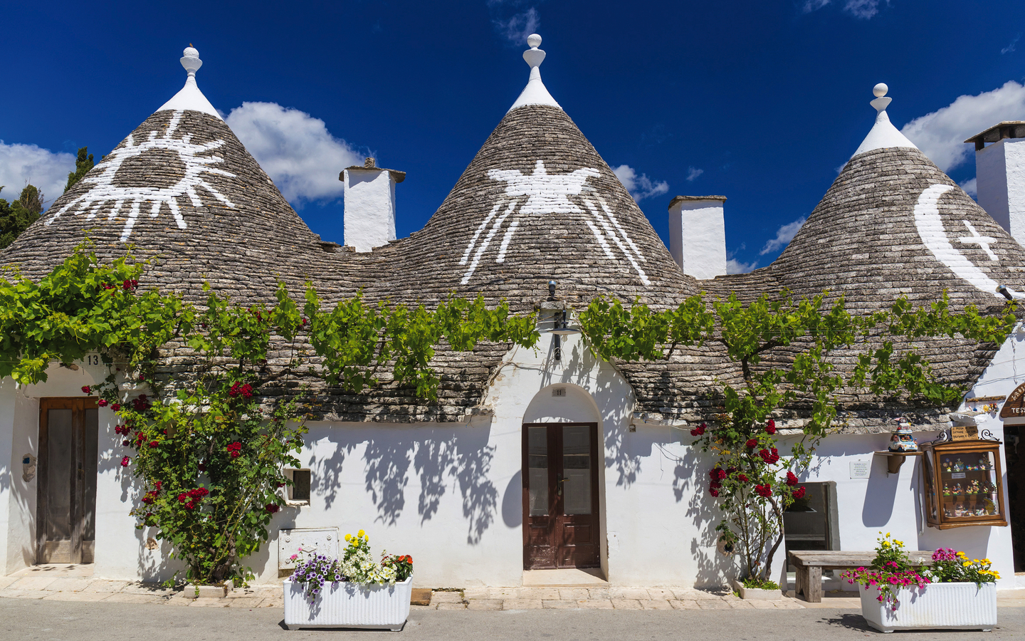 Trulli-Gebäude in Alberobello, Apulien, Italien mit dekorativen Dächern bei Sonnenschein.