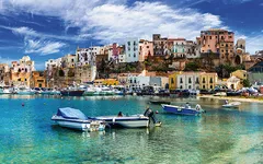 Blick auf Castellammare del Golfo mit Booten im klaren Wasser und historischen Gebäuden.