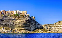 Küste von Bonifacio auf Korsika mit Klippen und Gebäuden bei klarem Himmel.