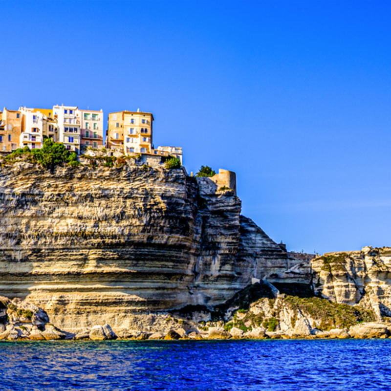 Küste von Bonifacio auf Korsika mit Klippen und Gebäuden bei klarem Himmel.