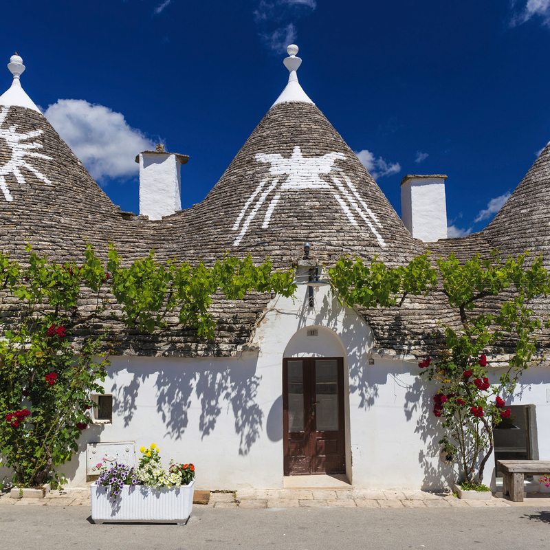 Trulli-Gebäude in Alberobello, Apulien, Italien mit dekorativen Dächern bei Sonnenschein.